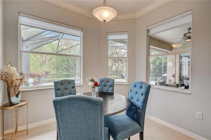 Tiled dining space with ceiling fan, plenty of natural light, and crown molding