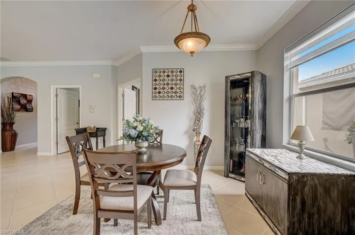 Tiled dining space featuring crown molding