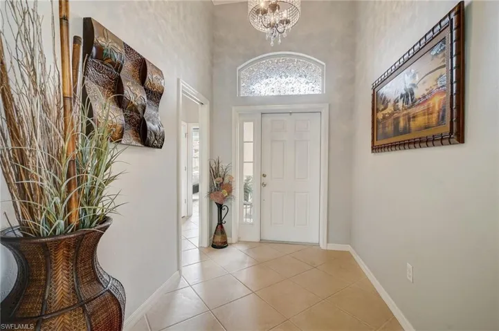 Tiled foyer entrance with a high ceiling and a notable chandelier