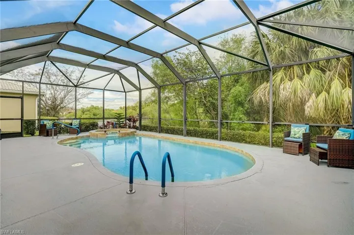 View of swimming pool with glass enclosure, an in ground hot tub, and a patio