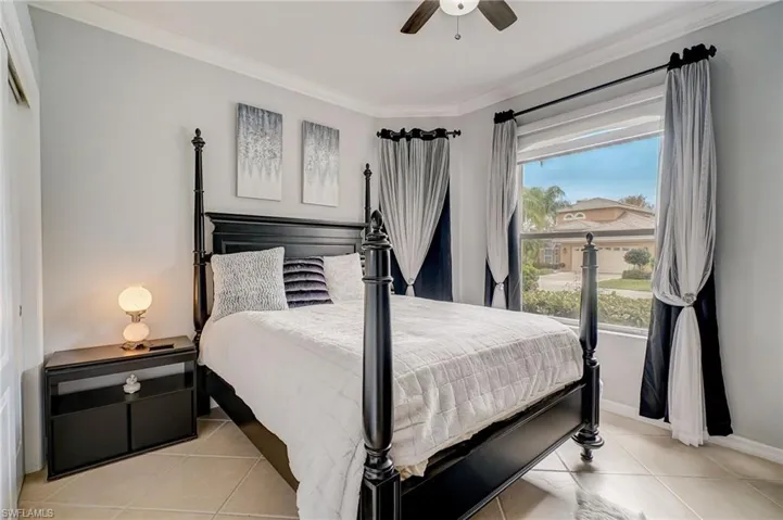 Tiled bedroom featuring ceiling fan and ornamental molding