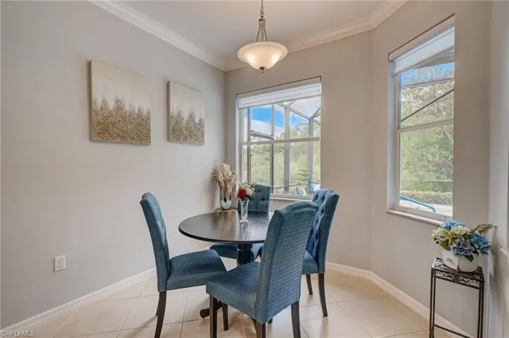 Dining area with a wealth of natural light, ornamental molding, and light tile patterned floors