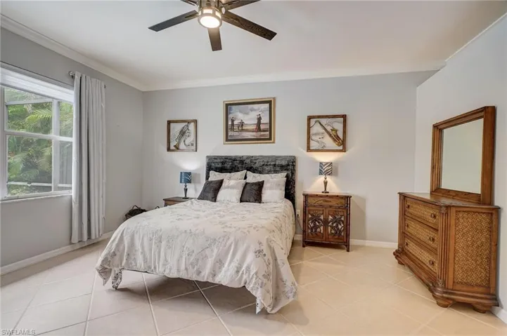 Tiled bedroom featuring ceiling fan and ornamental molding