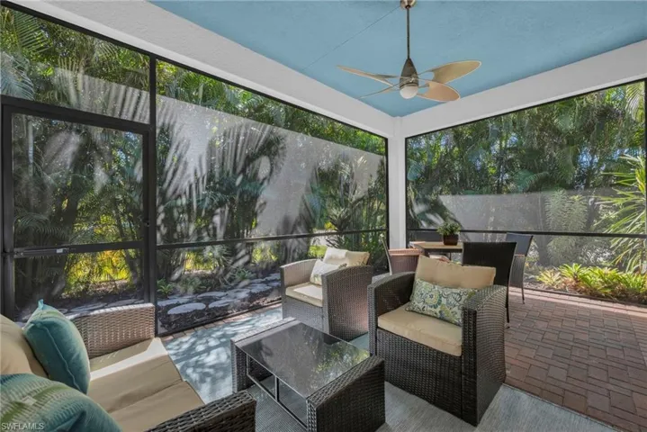 Screened lanai with ceiling fan and peaceful garden views, perfect for outdoor living.