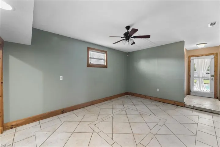 Unfurnished room featuring light tile patterned floors, a ceiling fan, visible vents, and baseboards