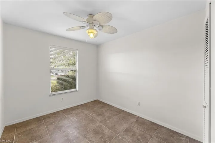 Empty room with tile patterned flooring, baseboards, and a ceiling fan