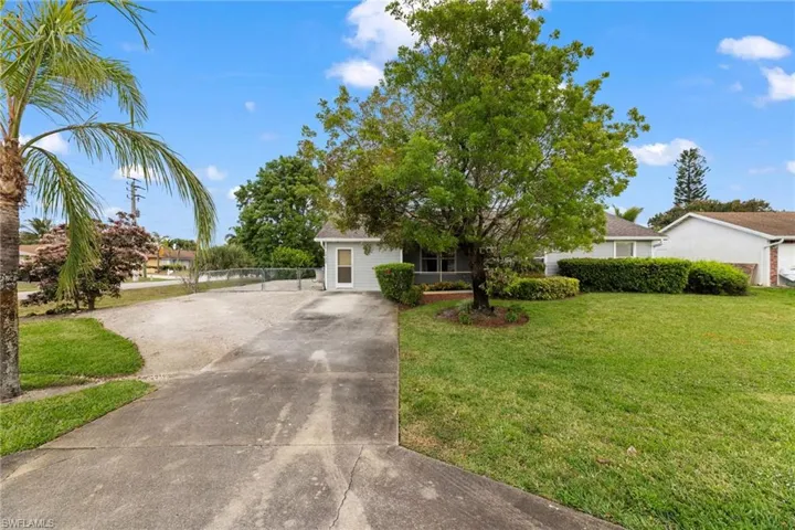 View of front of home featuring driveway, a front lawn, and fence