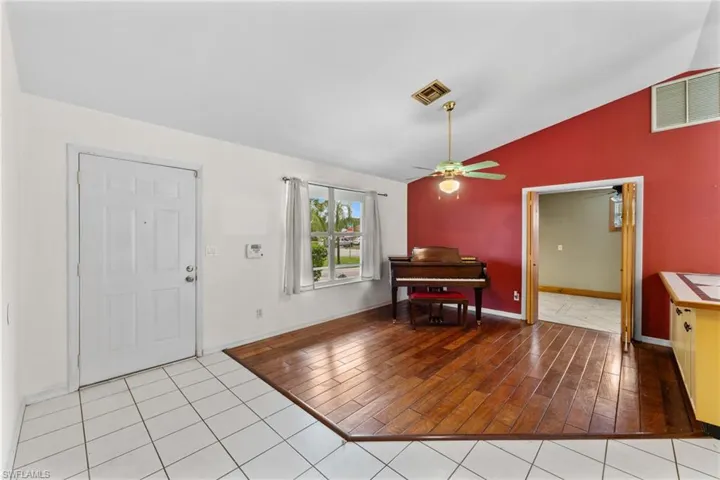 Foyer featuring vaulted ceiling, light wood-style floors, visible vents, and a ceiling fan