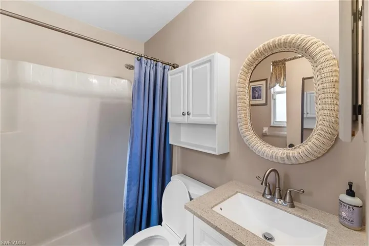 Bathroom with toilet, a shower with shower curtain, and vanity