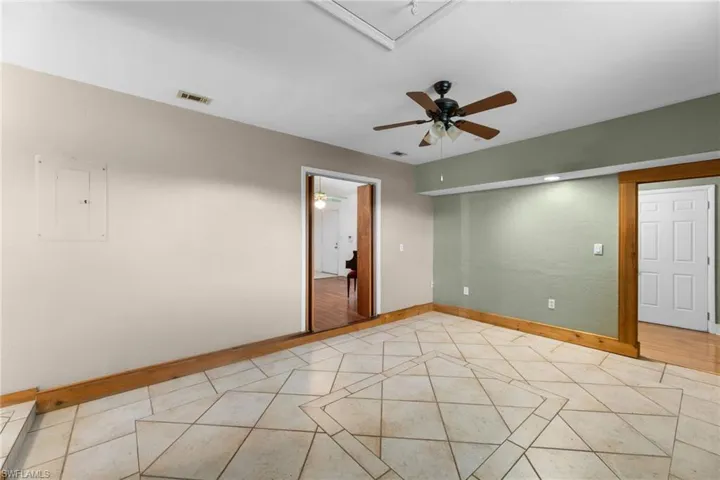 Spare room with light tile patterned floors, ceiling fan, visible vents, baseboards, and electric panel