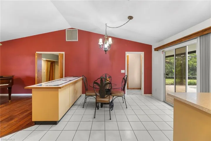 Dining space featuring baseboards, visible vents, vaulted ceiling, and a notable chandelier