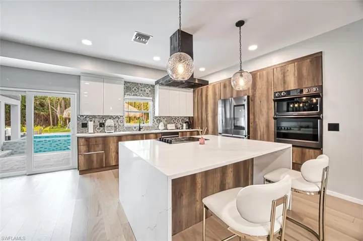 Kitchen with smart refrigerator, modern cabinets, white cabinetry, hanging light fixtures, and decorative backsplash