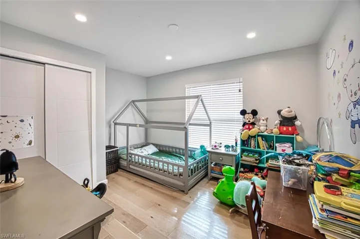 Bedroom with wood finished floors, recessed lighting, and a closet