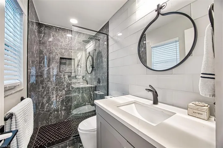 Full bath with tile walls, a marble finish shower, and vanity