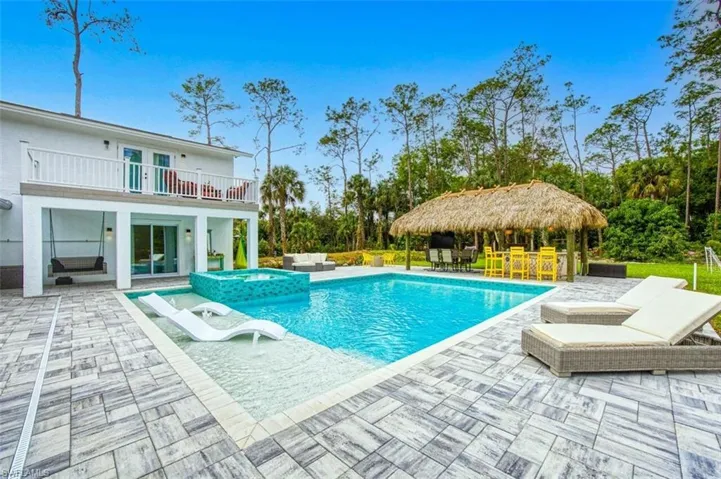 View of swimming pool featuring a patio, an outdoor hangout area, a gazebo, a pool with connected hot tub, and french doors