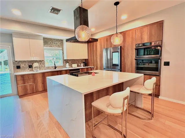 Kitchen featuring black appliances, brown cabinets, modern cabinets, light wood-style flooring, and recessed lighting