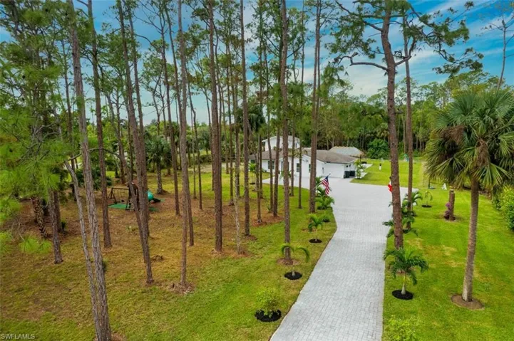 View of property's community with decorative driveway, a yard, and view of wooded area