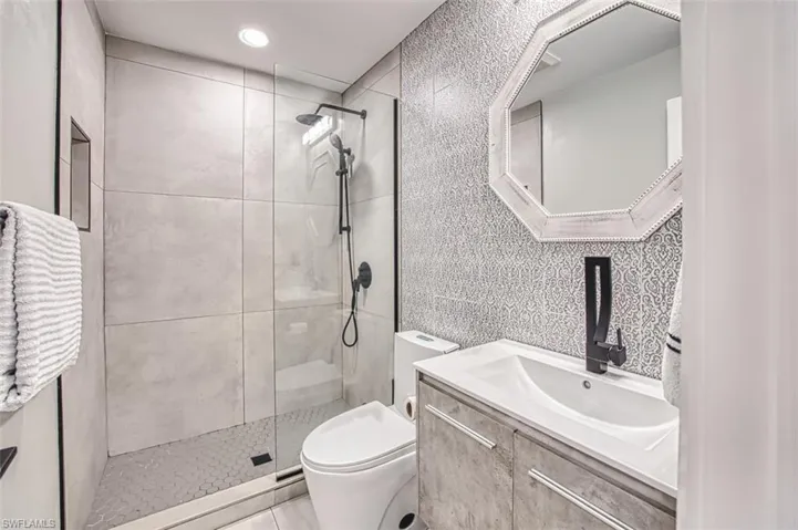 Full bathroom with tile walls, vanity, and tiled shower