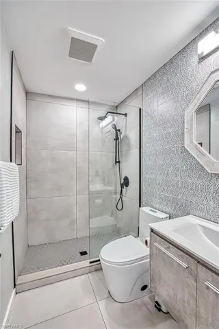 Full bathroom featuring a tile shower, vanity, and tile patterned floors