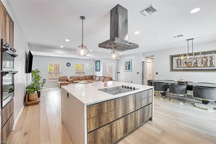 Kitchen featuring island exhaust hood, black electric cooktop, recessed lighting, modern cabinets, and a center island