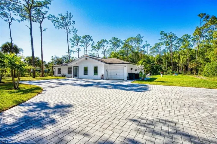View of front of property with an attached garage, driveway, and a front lawn