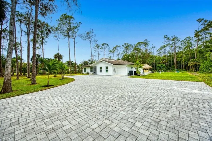 View of front of house featuring decorative driveway, an attached garage, and a front yard
