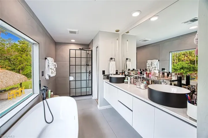 Full bath featuring double vanity, a freestanding tub, a tile shower, recessed lighting, and tile patterned flooring