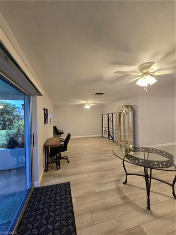 Living area with a textured ceiling, ceiling fan, and light hardwood / wood-style floors