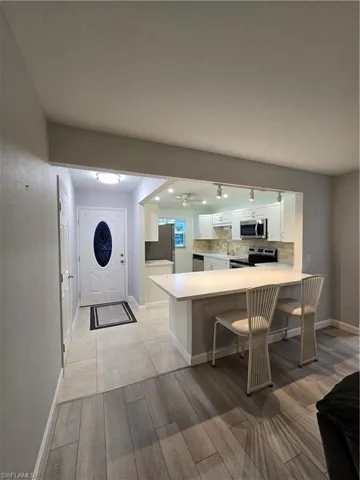 Kitchen with light wood-type flooring, white cabinetry, stove, kitchen peninsula, and a breakfast bar area
