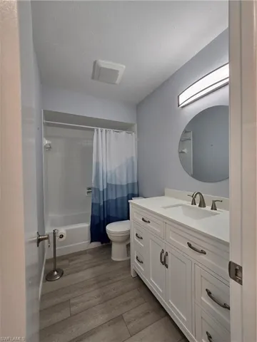 Full bathroom with toilet, hardwood / wood-style floors, vanity, a textured ceiling, and shower / bath combo