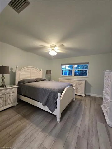 Bedroom with a textured ceiling, wood-type flooring, and ceiling fan