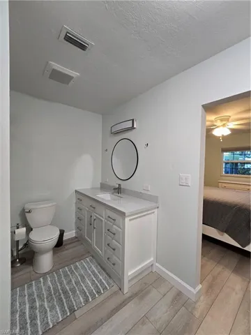 Bathroom featuring vanity, toilet, hardwood / wood-style floors, and a textured ceiling