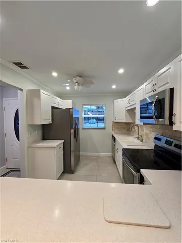 Kitchen with stove, sink, ceiling fan, stainless steel dishwasher, and white cabinets