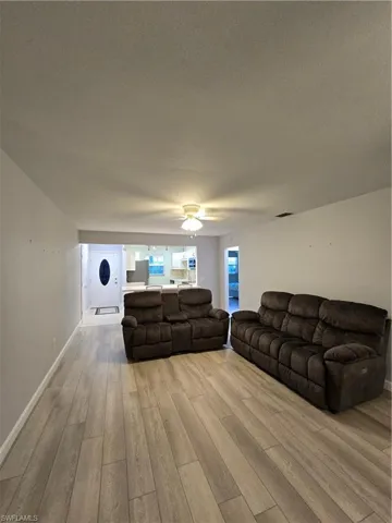 Living room featuring a textured ceiling, light hardwood / wood-style flooring, and ceiling fan