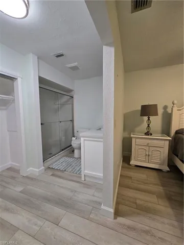 Bathroom with toilet, vanity, a textured ceiling, hardwood / wood-style flooring, and a shower with shower door
