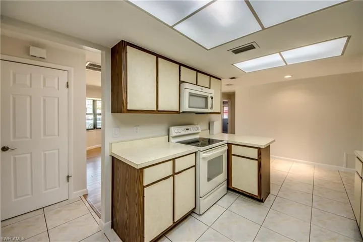 Kitchen with white appliances, light countertops, light tile patterned floors, and a peninsula