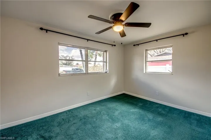 Unfurnished room featuring dark colored carpet and a ceiling fan