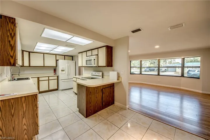 Kitchen featuring white appliances, light countertops, light tile patterned flooring, wood finish cabinets, and a peninsula