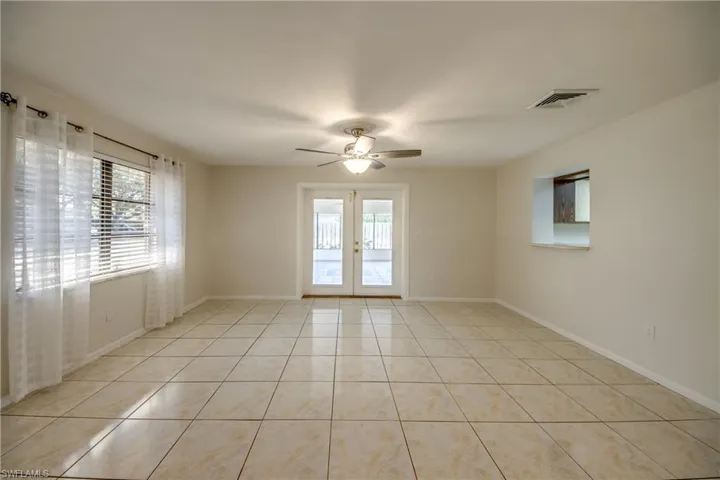 Empty room with french doors, ceiling fan, and light tile patterned floors