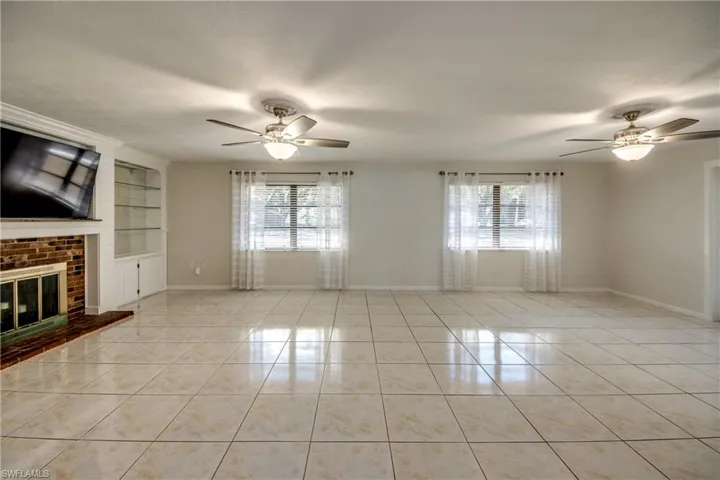 Unfurnished living room featuring a ceiling fan, light tile patterned flooring, and built in shelves