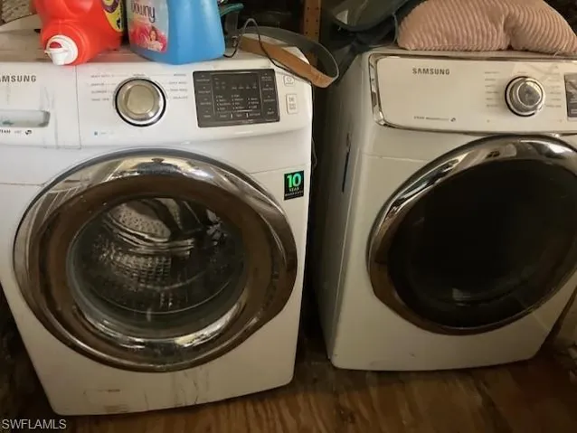 Clothes washing area featuring washer and clothes dryer and dark hardwood / wood-style flooring