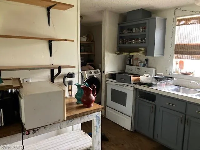 Kitchen with white range, sink, a textured ceiling, and washer / clothes dryer