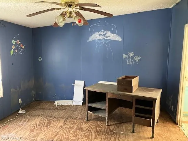 Home office with ceiling fan, a textured ceiling, and hardwood / wood-style flooring
