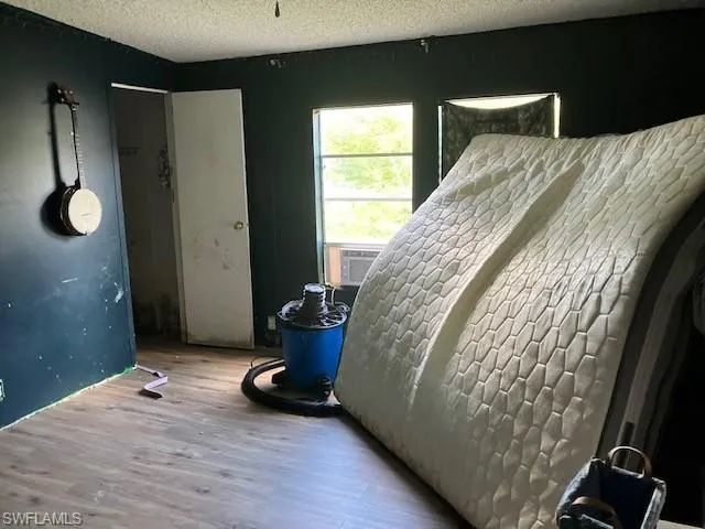 Bedroom featuring hardwood / wood-style flooring, a textured ceiling, and cooling unit