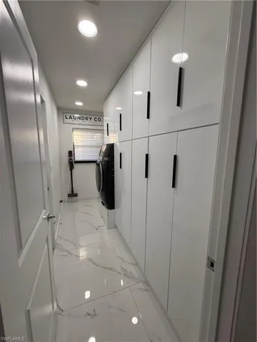 Hall with recessed lighting, independent washer and dryer, and light marble finish floors