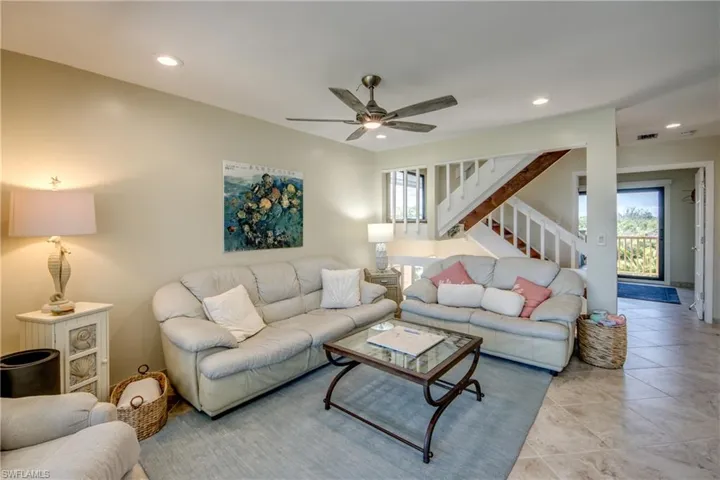 Tiled living room with stairs, a ceiling fan, visible vents, and recessed lighting