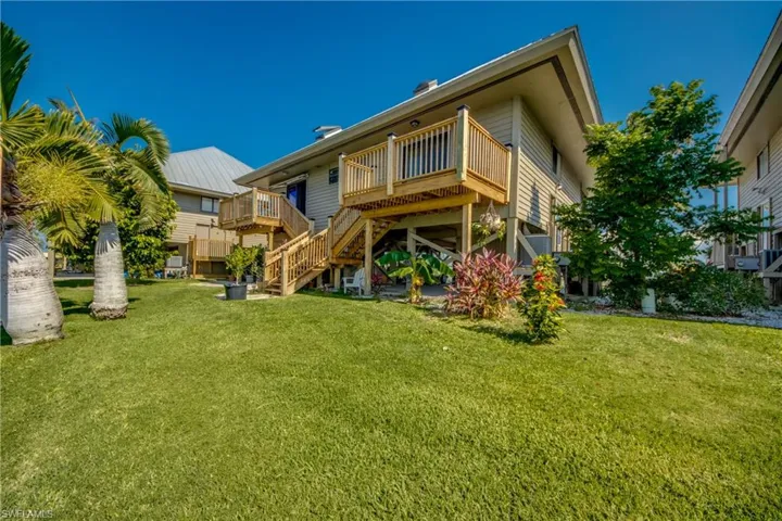 Back of property featuring a deck, stairway, and a lawn