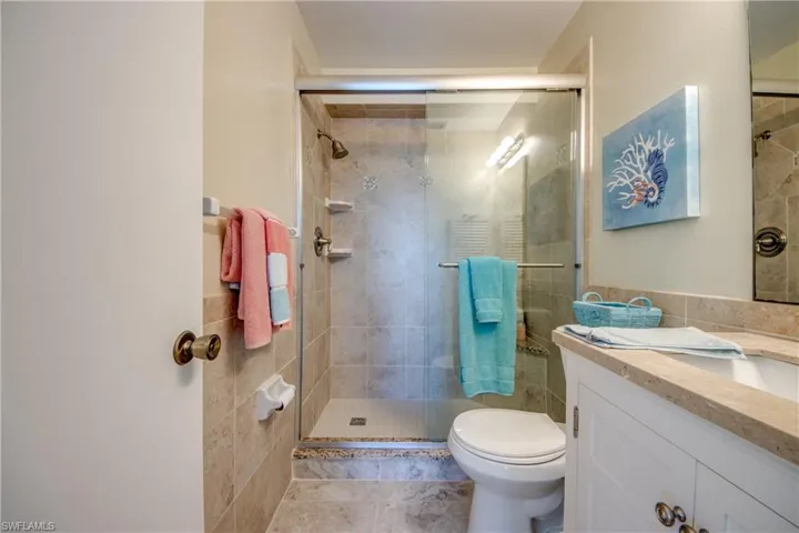Full bath with toilet, tile patterned flooring, vanity, a shower stall, and tile walls