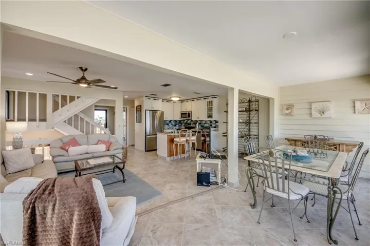 Living room featuring a ceiling fan, stairway, wooden walls, and light tile patterned floors