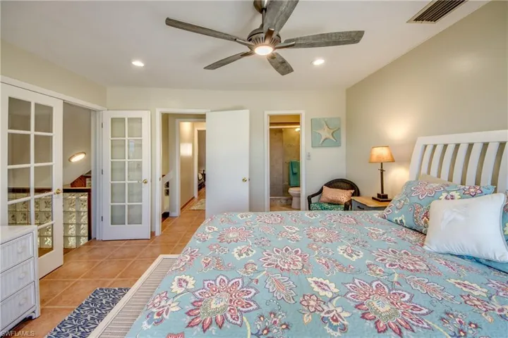 Bedroom with french doors, light tile patterned floors, recessed lighting, visible vents, and ensuite bathroom